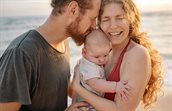 vader en moeder met baby op het strand